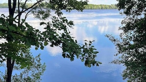 Eine Holztreppe führt zu einem Steg an einem stillen See, umgeben von Bäumen.