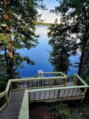 Une terrasse en bois qui mène à un lac, avec des arbres encadrant le paysage.