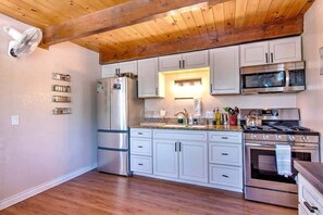 Une cuisine avec des poutres en bois, des appareils électroménagers en acier inoxydable et des meubles de couleur claire.