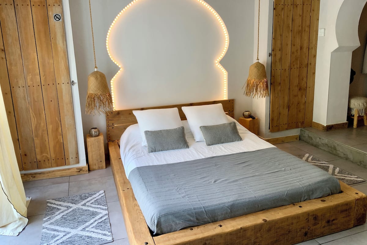 Une chambre à coucher avec un lit en bois, une literie blanche et une tête de lit dotée de lumières LED.