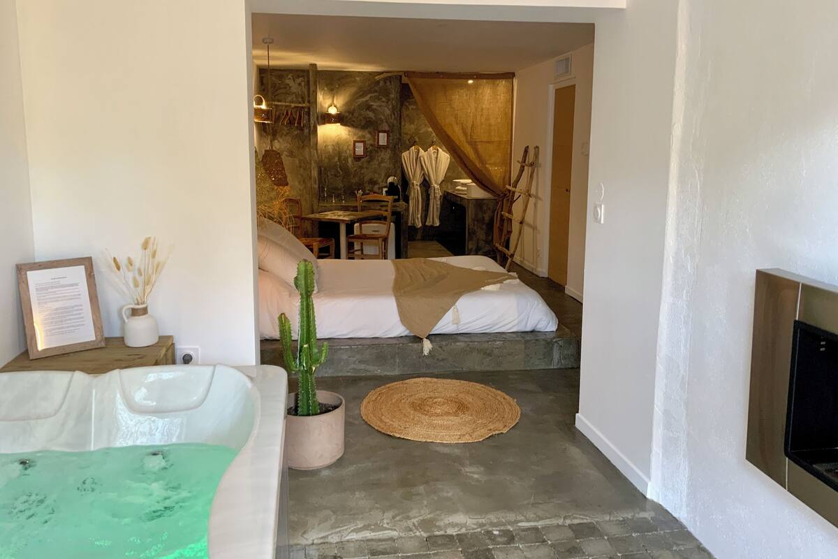 Une chambre d’hôtel moderne avec un mur en pierre, un lit, une petite table et une cheminée.