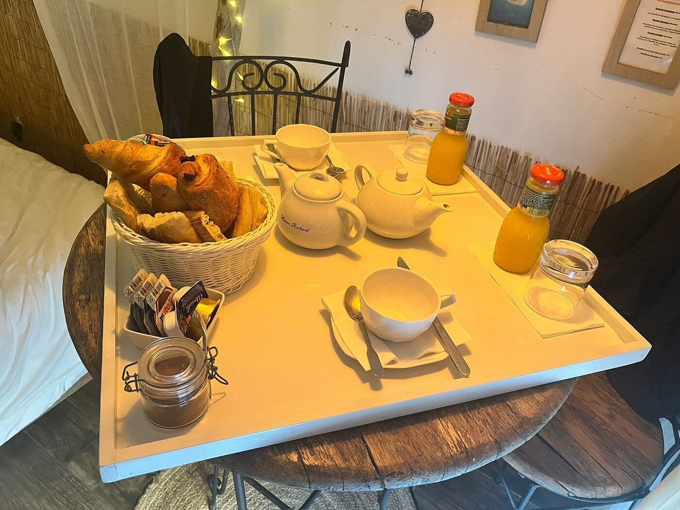 A breakfast tray with croissants, tea, and orange juice on a wooden table.