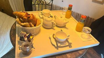 Una bandeja de desayuno con cruasanes, té y jugo de naranja sobre una mesa de madera.