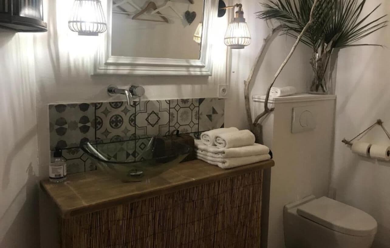 A bathroom with a glass sink, a mirror, a toilet, and a towel rack.