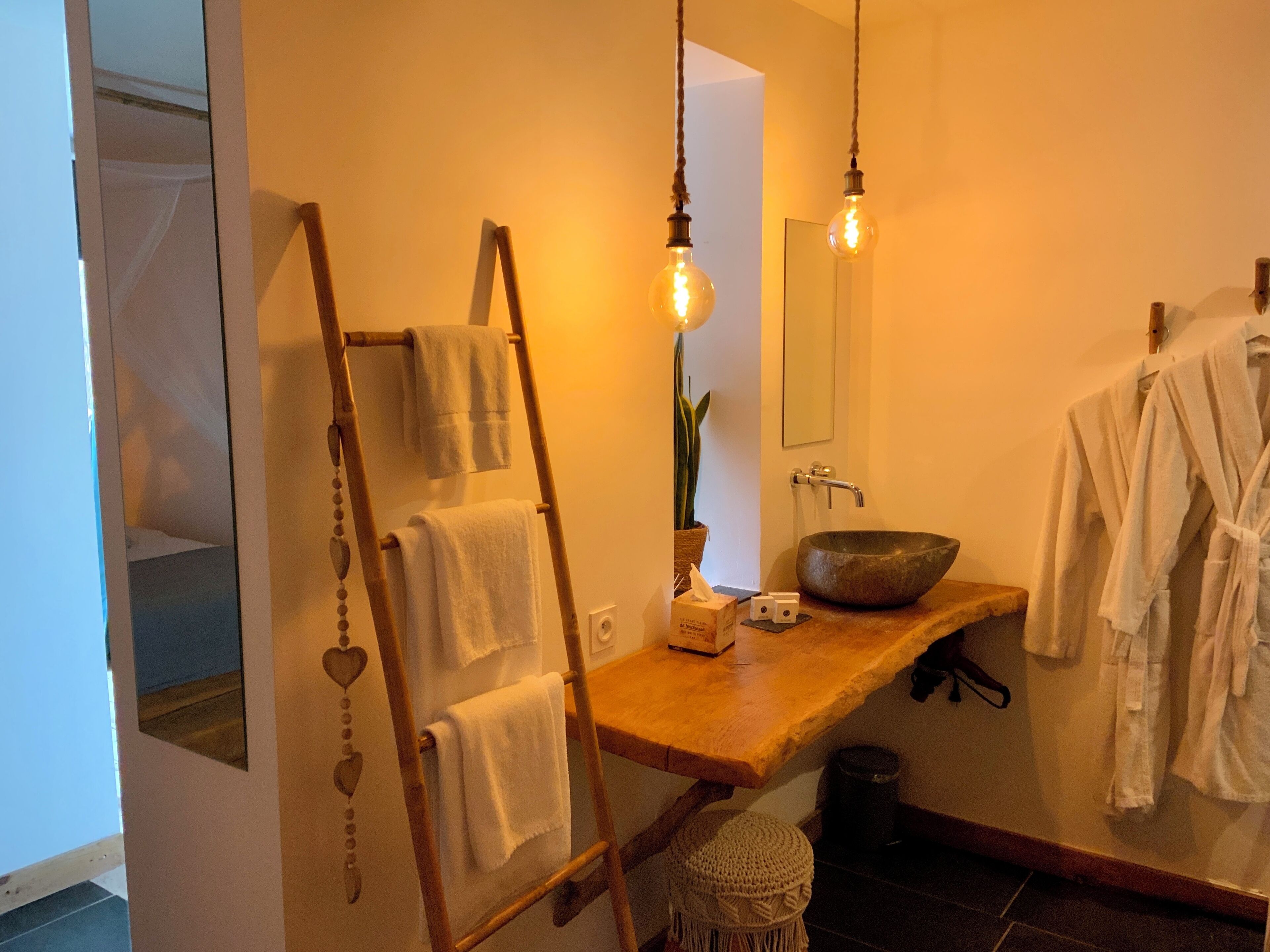A bathroom with a wooden vanity, a large mirror, a stone sink, and hanging towels.