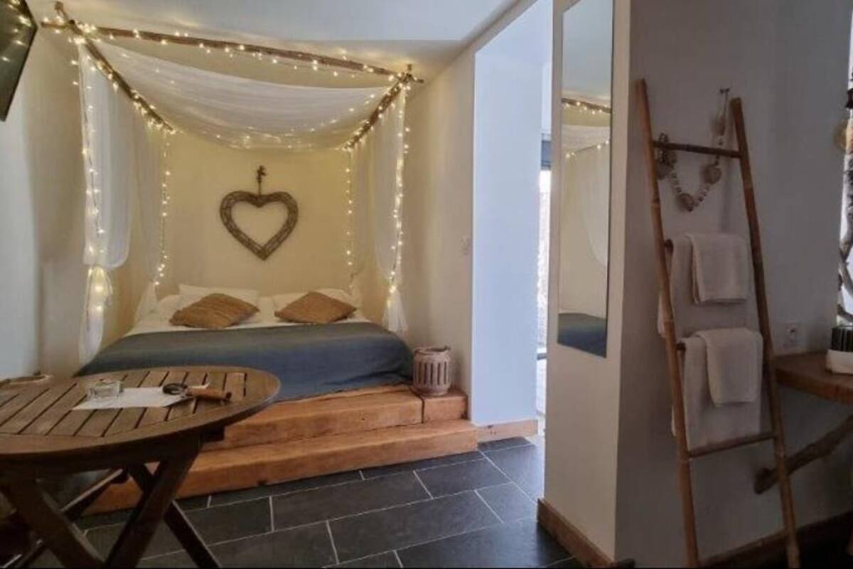 Une chambre confortable avec un lit, une table de chevet et un petit coin salon comprenant une table et des chaises.