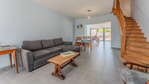 A spacious living room with a grey sofa, wooden coffee table, and a wooden staircase.