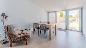A dining area with a wooden table and chairs, a lamp, and a view through a glass door to the outside.