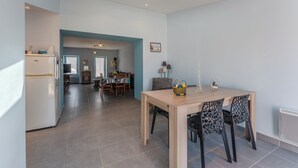 A modern kitchen with a built-in refrigerator, a dining area with a wooden table and black chairs, and a skylight above the kitchen.