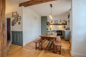 A kitchen with a wooden table and benches, a hanging light fixture, and a clock on the wall. - Break en Sarthe - Wifi - Jardin (Bessé-sur-Braye)