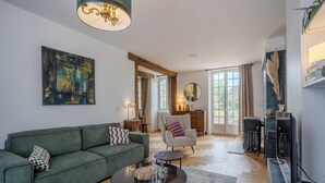Een moderne woonkamer met een groene bank, een ronde salontafel en een tv-meubel.