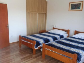 Une chambre avec deux lits en bois, une armoire et un tableau encadré au mur.