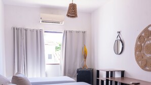 Habitación de hotel con dos camas, un escritorio, una silla, un espejo y una lámpara colgante.