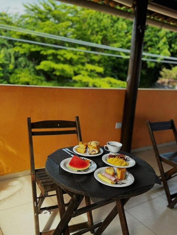 A round table with chairs on a balcony, surrounded by a wooden railing.