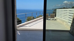 Un balcón con vistas al mar, una valla blanca y un muro de piedra.