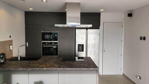 Una cocina moderna con horno empotrado, extractor de acero inoxidable y una puerta blanca.