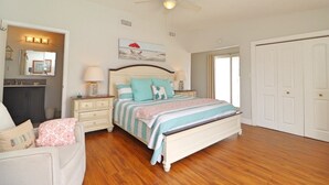 A bedroom with a bed, bedside tables, a ceiling fan, a dresser, and a door. - Sunny house with pool, just steps to the beach! (Ormond Beach)