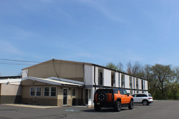 Two-story building with a flat roof and covered parking area, featuring a single entrance and door number.