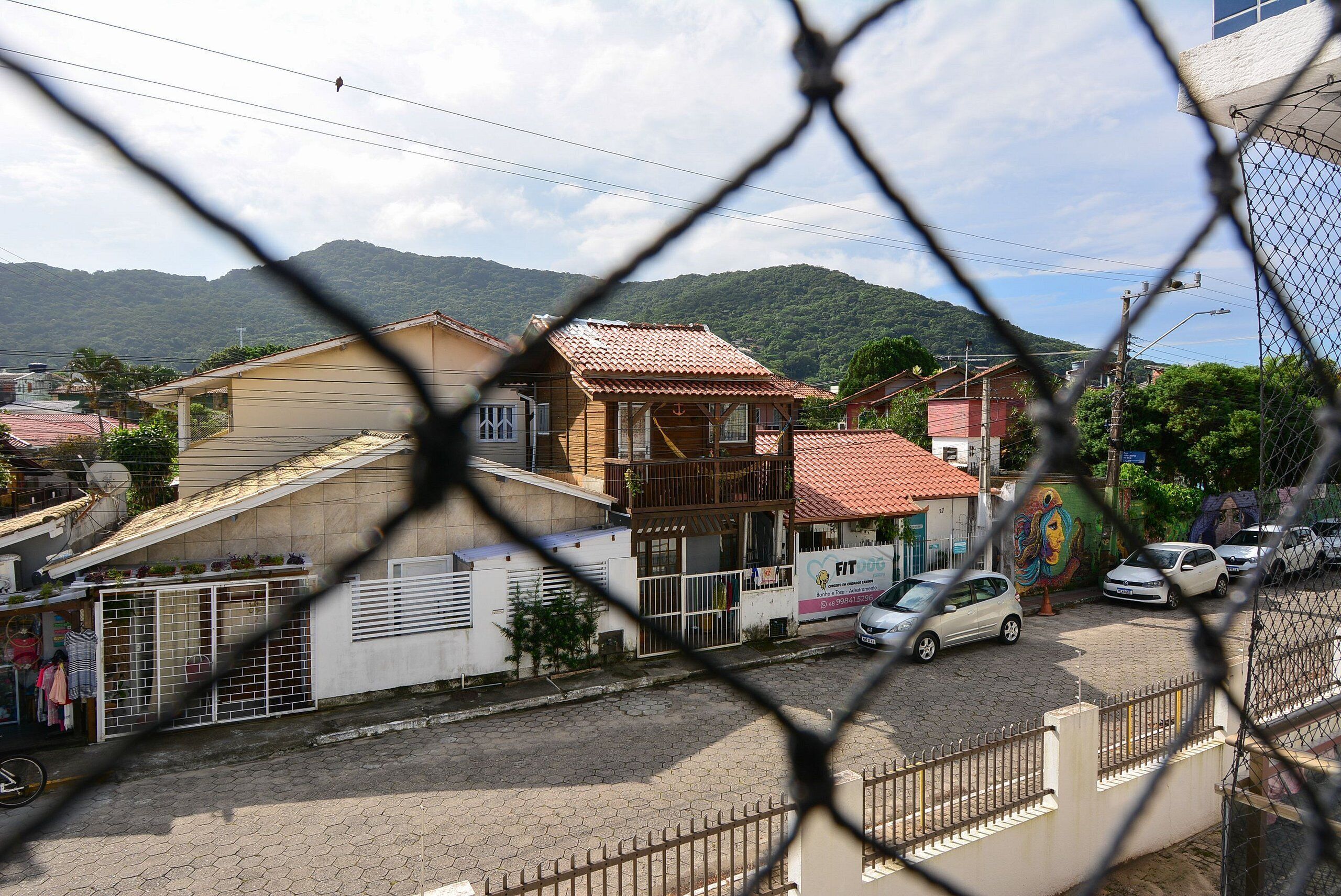 Una calle residencial con casas, un mural y una montaña al fondo.