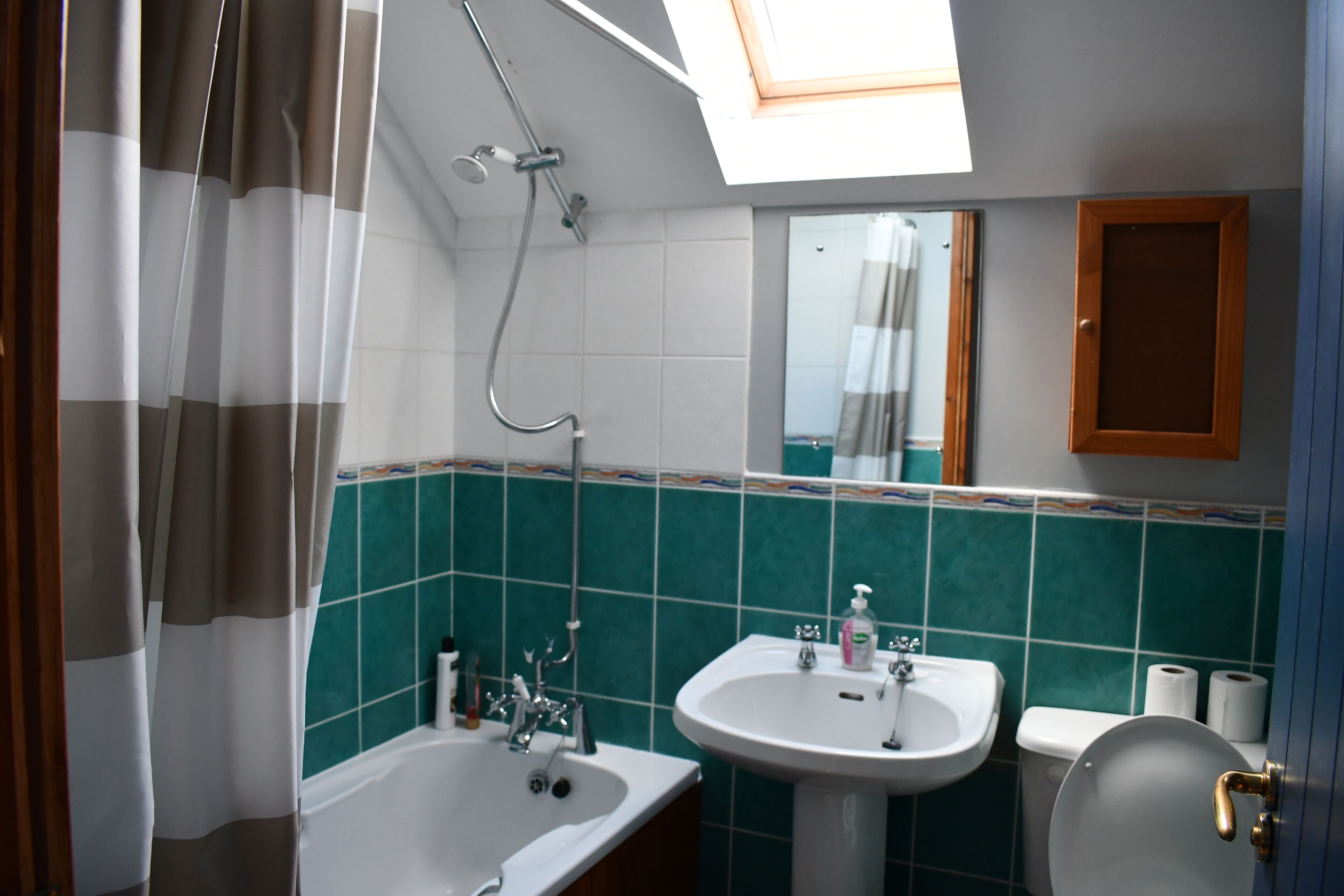 Un baño con tragaluz, bañera, lavamanos e inodoro.