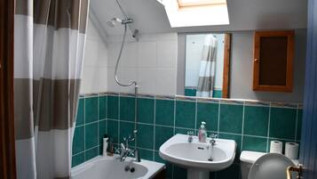 Un baño con tragaluz, bañera, lavamanos e inodoro.
