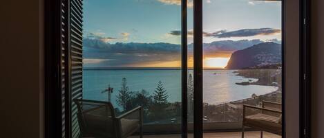 Enjoy a scenic coastal view from the balcony, featuring a comfortable seating area with a chair and bench.