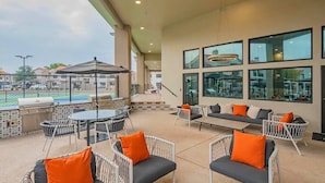 Eine Terrasse im Freien mit Sitzgelegenheiten, einem Grill und Blick auf einen Swimmingpool.