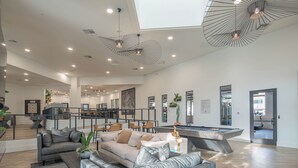A spacious living area with a pool table, sofas, and a high ceiling with modern lighting fixtures. - Sunset Retreat | Patio | Ground Floor | Kierland (Scottsdale)