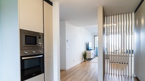 Une cuisine moderne dotée d’appareils électroménagers intégrés, d’un plancher en bois et donnant sur un espace de vie avec balcon.