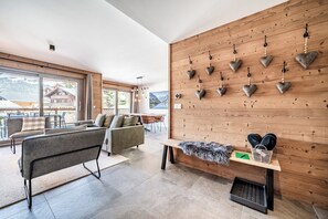 Ein modernes Interieur mit einer Couch, einer Sitzbank, einer Holzwand mit herzförmigen Verzierungen und Blick ins Freie.
