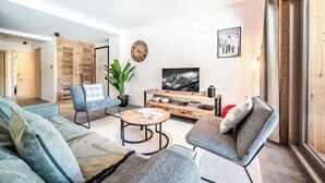 A modern living room with a sofa, armchair, coffee table, and a TV.