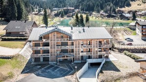 A multi-story building with a ski lift, surrounded by a mountainous landscape and a lake.