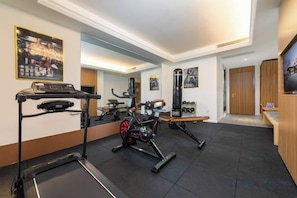 A gym with exercise equipment, a treadmill, and a mirror.