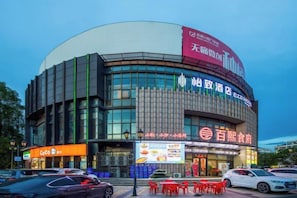 A modern building with a curved facade, large windows, and multiple signs indicating commercial use.