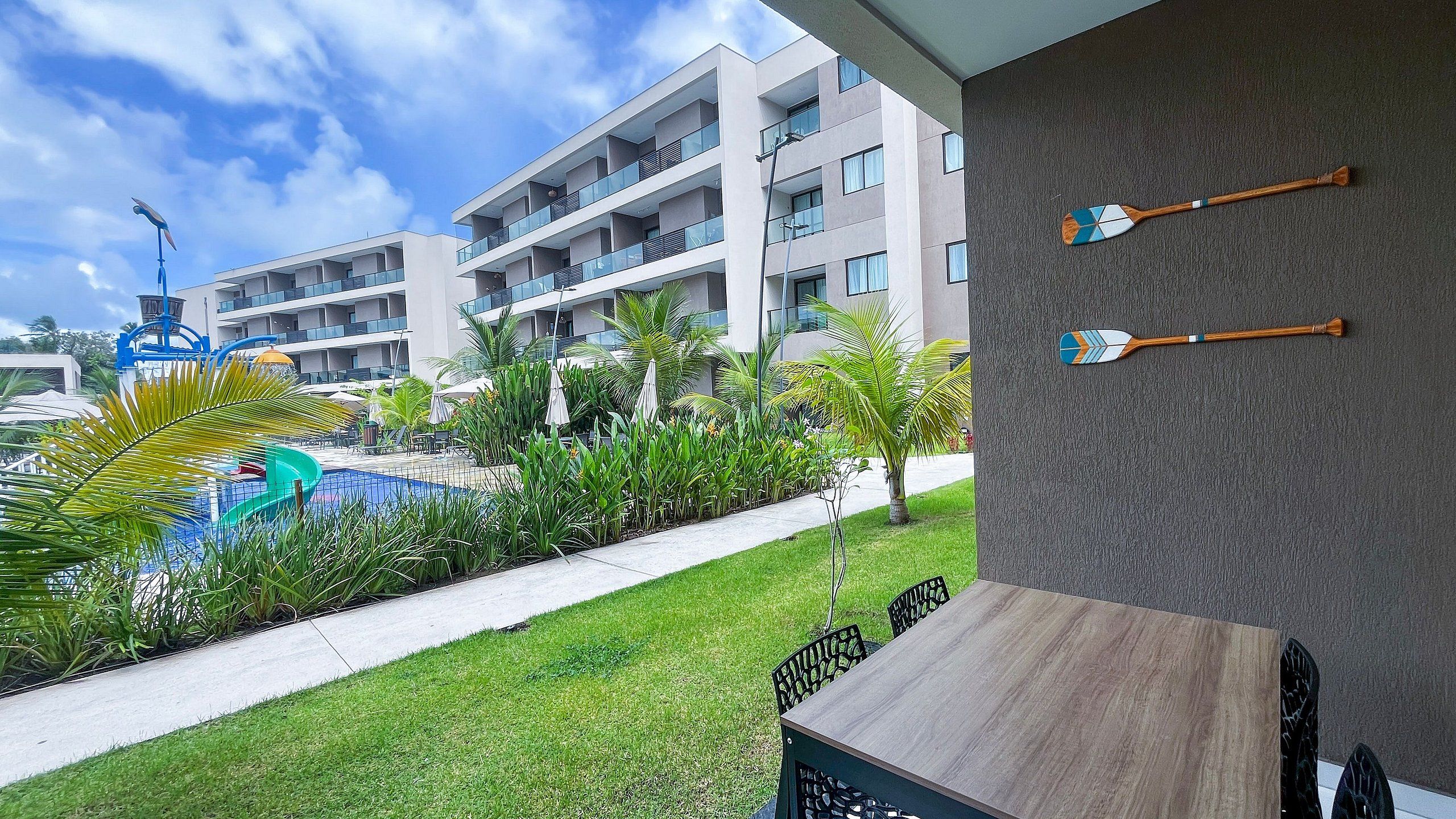 Un hôtel moderne doté d’une piscine, d’un espace extérieur aménagé et offrant une vue sur les balcons de l’immeuble.