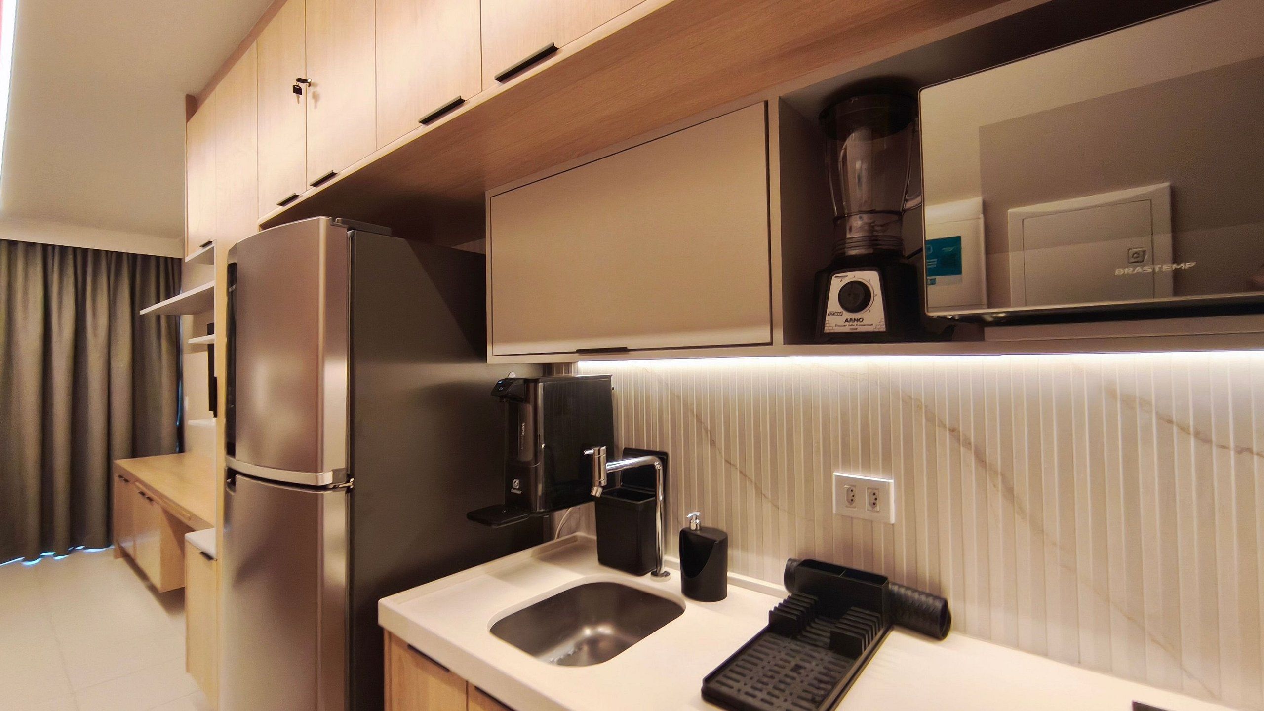 A compact kitchenette with a refrigerator, coffee maker, and a microwave.
