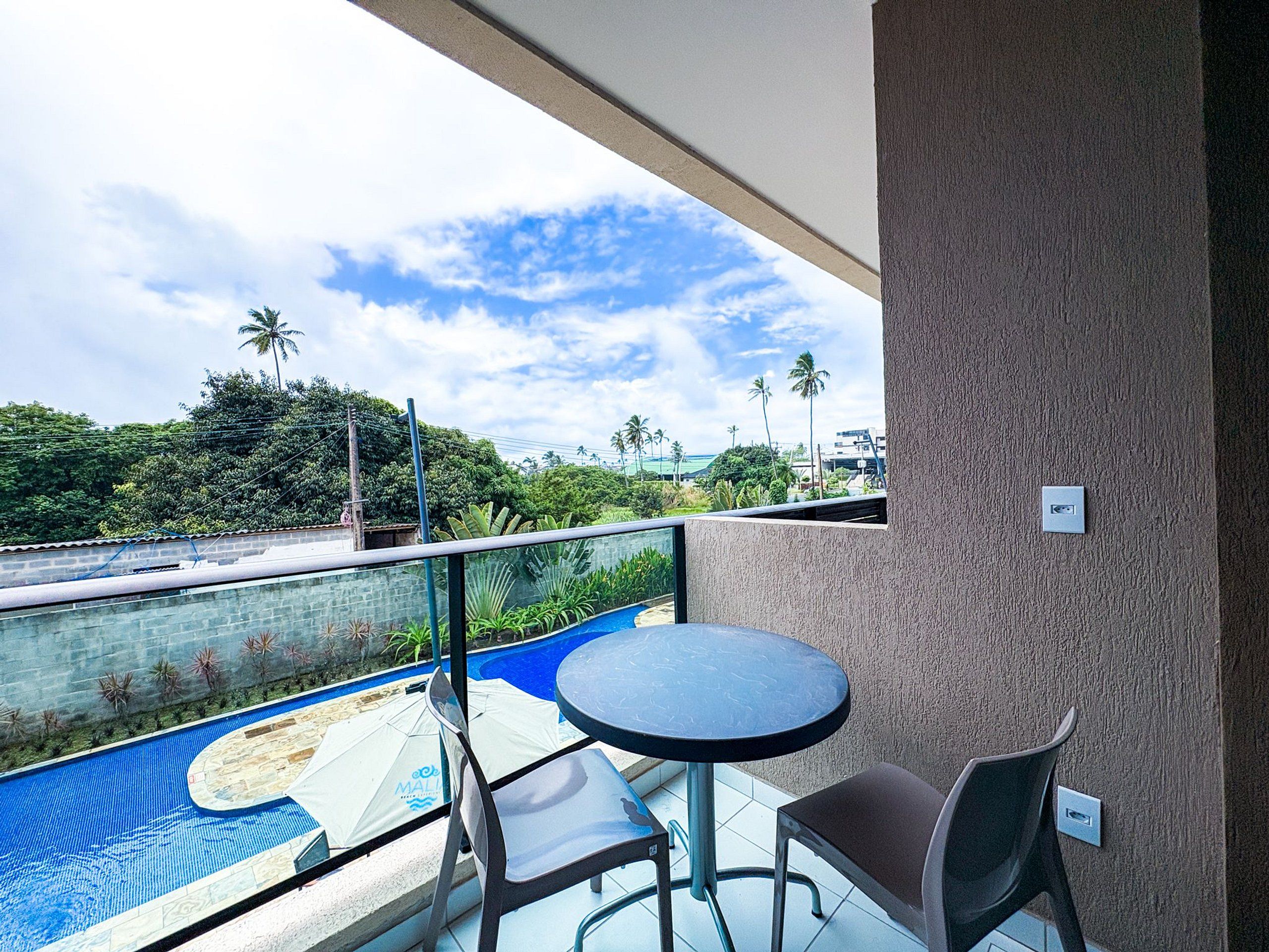 A balcony with a pool, chairs, and a table.