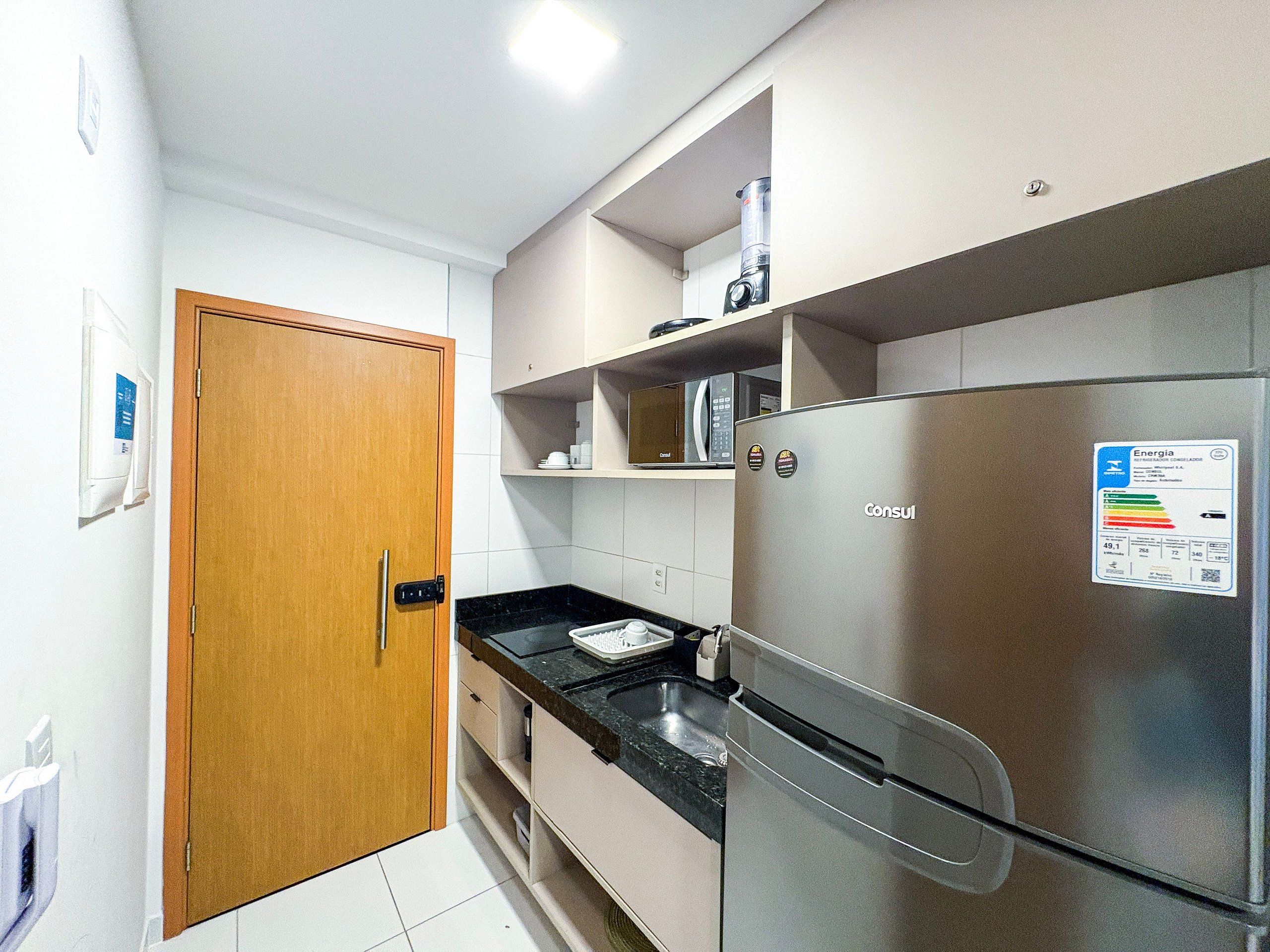 Eine kleine Küche mit Kühlschrank, Mikrowelle und Spüle.