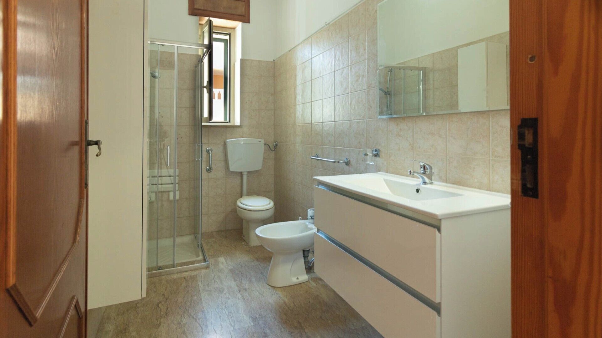 A bathroom with a glass shower enclosure, a toilet, and a sink with a mirror above it.