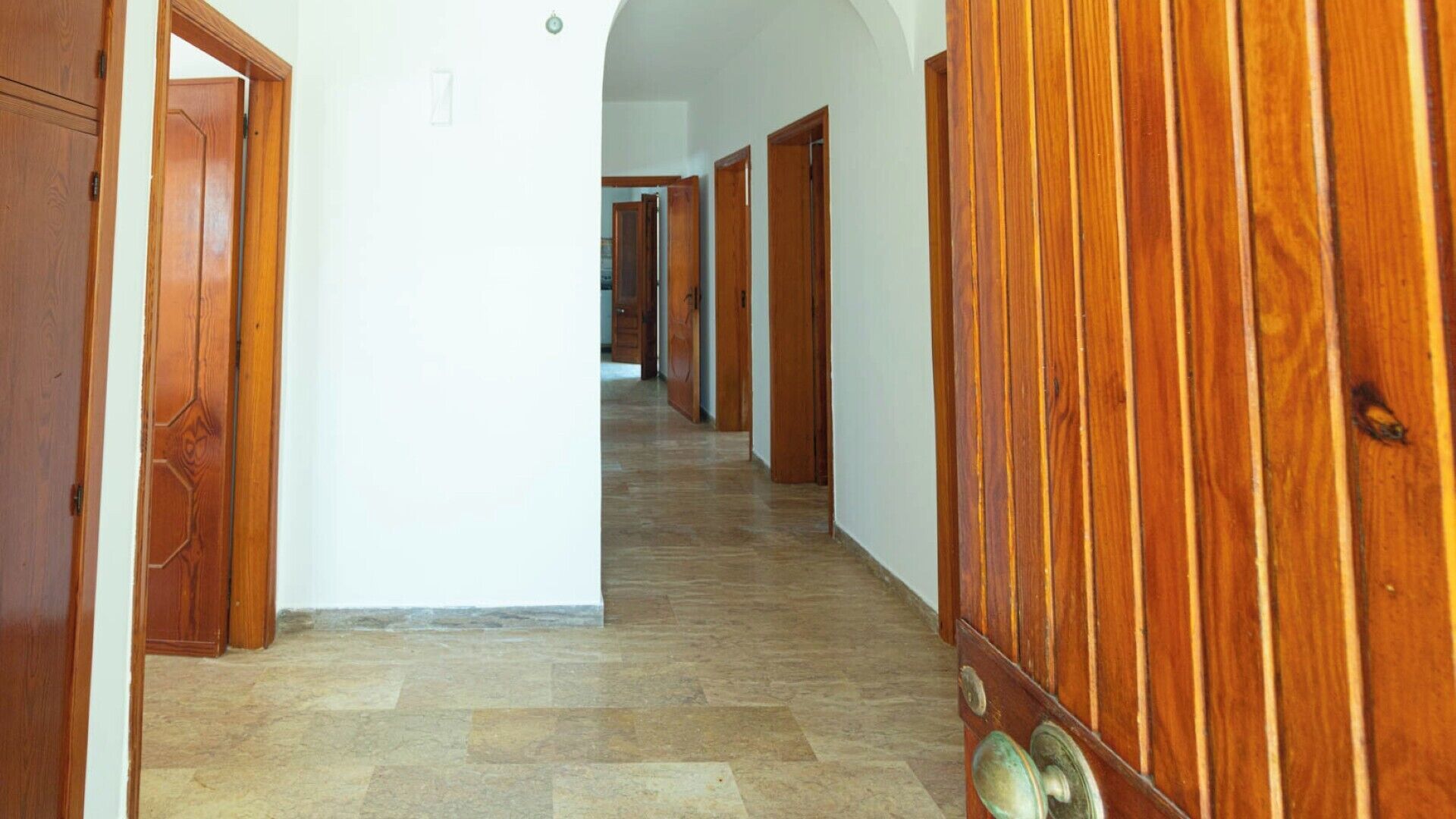 A hallway with wooden doors and a tiled floor.