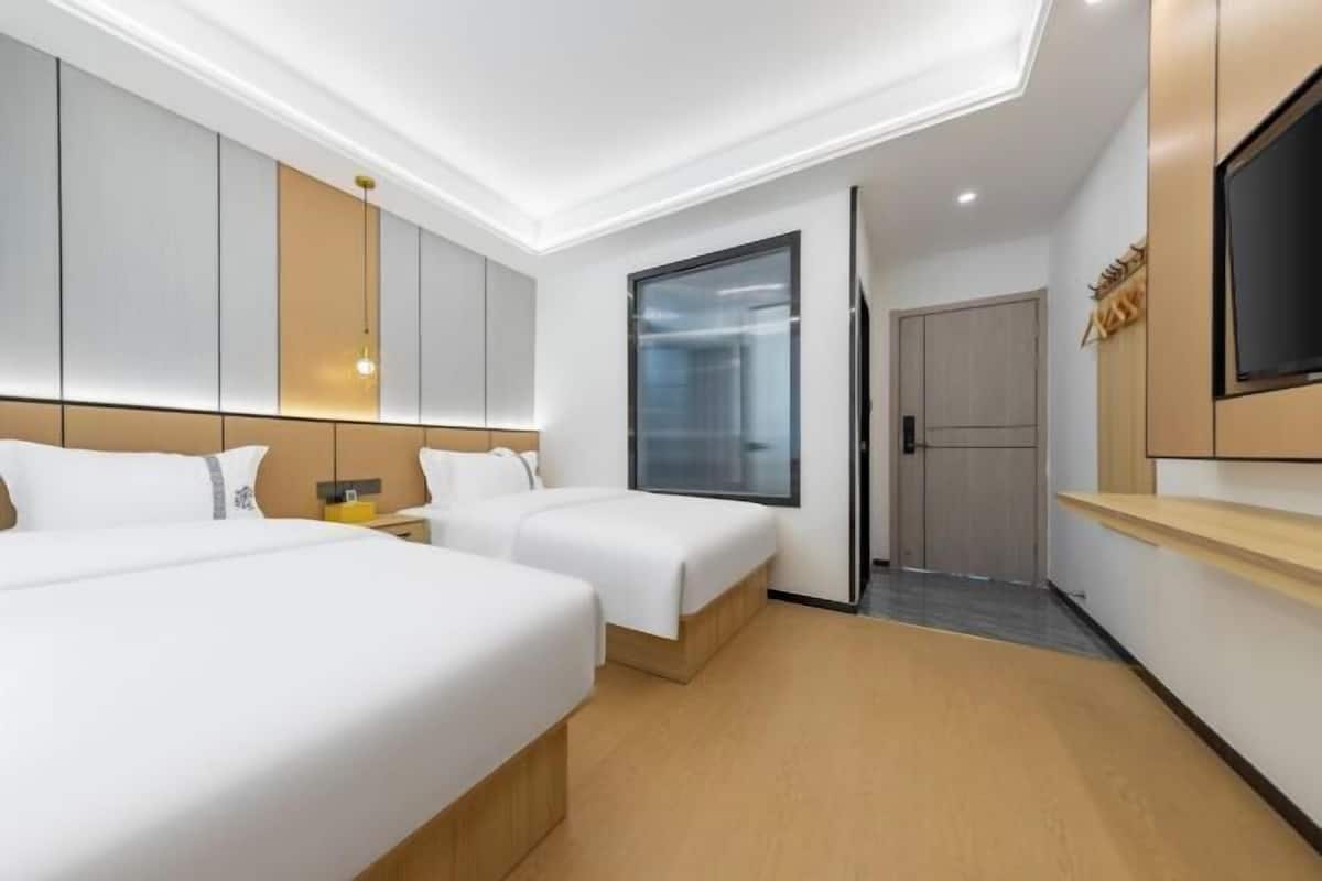 A hotel room with two beds, a TV, a wardrobe, and a door leading to a bathroom.