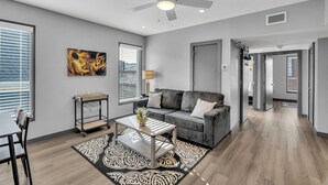 A modern living room with a grey sofa, a coffee table, and a ceiling fan. - New Orleans Bywater Apartments (New Orleans)