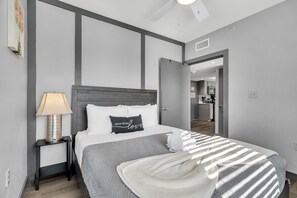 Un dormitorio moderno con una cama, un mesita de noche, una lámpara y vistas a la cocina.