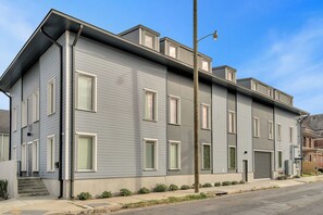 Un edificio de dos pisos con fachada gris, varias ventanas y una entrada visible con escalones.