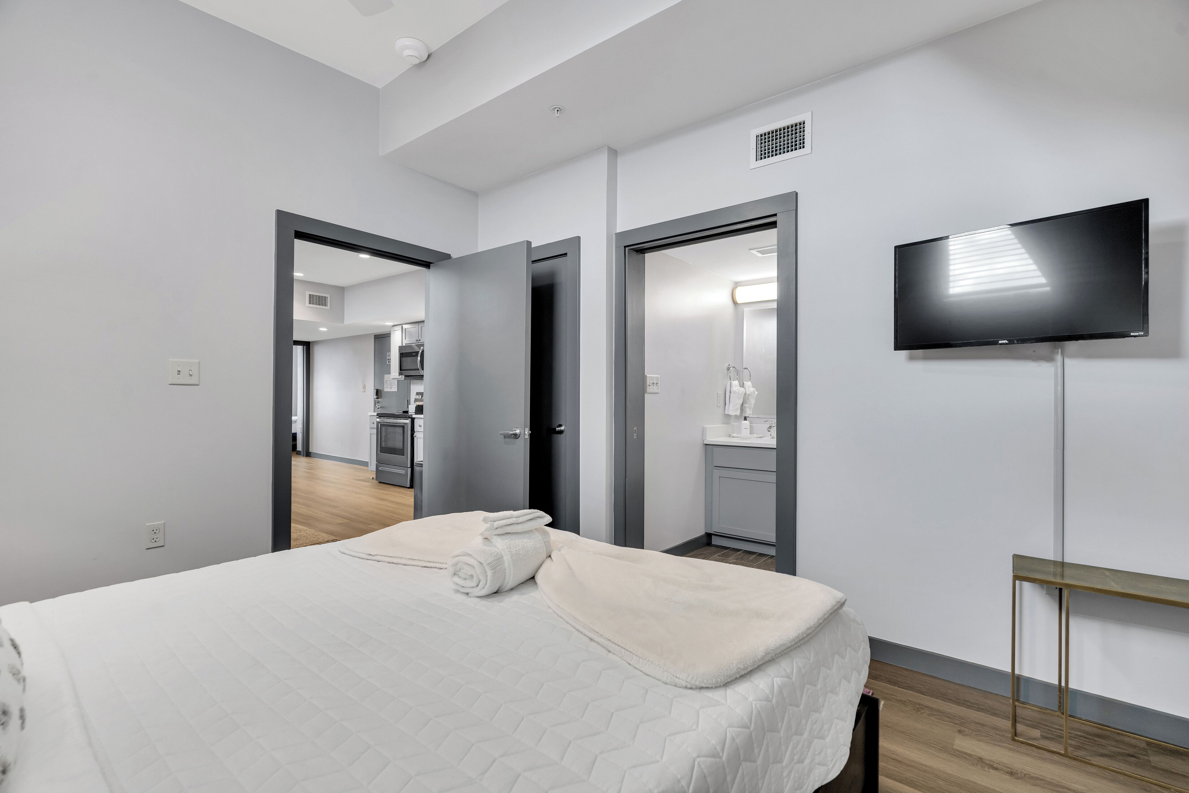 Una habitación de hotel moderna con una cama, un televisor y una kitchenette al fondo.