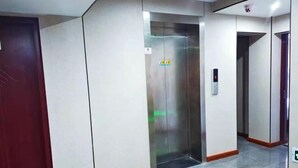 A modern elevator with a digital control panel, a red door to the left, and a tiled floor. - Guanhu Hotel (Hangzhou West Lake Hefang Street) (Hangzhou)