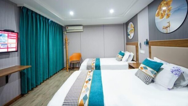 A hotel room with two beds, teal curtains, a TV, and a wall-mounted air conditioner. - Guanhu Hotel (Hangzhou West Lake Hefang Street) (Hangzhou)