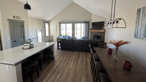 A spacious kitchen with a central island, a dining area with a long table, and a living area with a large sofa. - Spacious Mountain Retreat on Golf Course, near Rocky Mountain National Park (Granby)