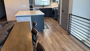 A modern kitchen with a central island, a dining area with a wooden table and chairs, and a living area with a sofa. - Spacious Mountain Retreat on Golf Course, near Rocky Mountain National Park (Granby)