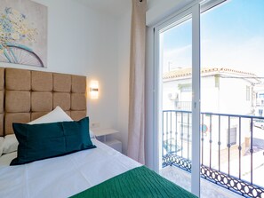 Ein Hotelzimmer mit einem großen Bett, einem Kopfteil, einer Wandleuchte und Blick auf den Balkon.